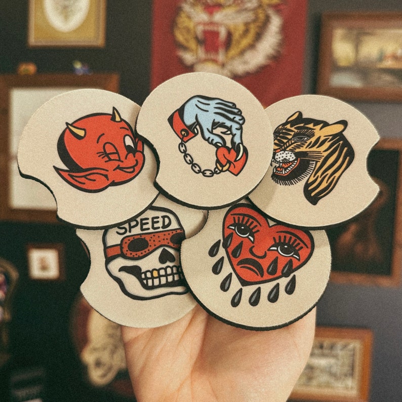 Puede incluir: Conjunto de seis posavasos coloridos con varias ilustraciones. Los posavasos son redondos y presentan un diablo rojo, una mano con un coraz&oacute;n, un tigre, una calavera con gafas, un coraz&oacute;n que llora y un gr&aacute;fico de velocidad.