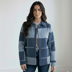 May include: A blue and grey patchwork jacket with a collared neckline and button closure. The jacket has a geometric design with visible stitching. The model is wearing a grey t-shirt and blue jeans.