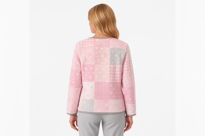 Pu&ograve; includere: Un top rosa a maniche lunghe con patchwork e rifiniture grigie intorno allo scollo e ai polsini. Il top presenta vari quadrati rosa e grigi a fantasia, tra cui stelle e quadretti. La modella indossa pantaloni grigi.