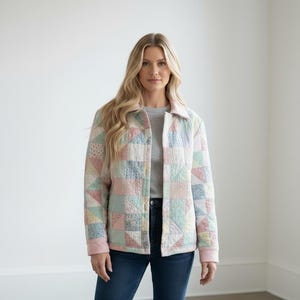 Pu&ograve; includere: Giacca trapuntata dai colori pastello, con un design patchwork di quadrati e triangoli rosa, blu e crema. La giacca ha un colletto e viene indossata sopra un top grigio e jeans blu.