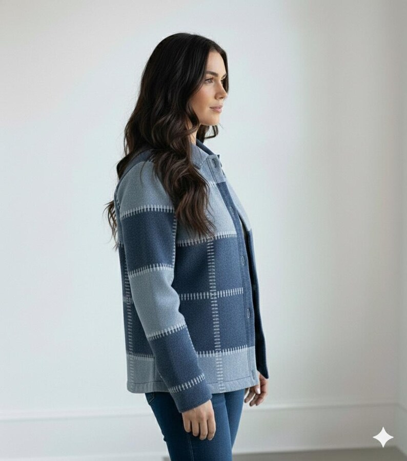 May include: A blue and grey patchwork jacket with a button-up front. The jacket has a plaid design with visible stitching. The sleeves are long, and the jacket is worn with blue jeans. The overall style is casual and comfortable.