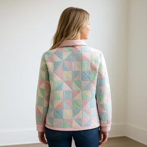 Pu&ograve; includere: Giacca trapuntata color pastello con un motivo geometrico a triangoli. La giacca presenta un colletto e finiture rosa chiaro, con un mix di triangoli rosa, blu, verdi e gialli. La giacca &egrave; indossata sopra un paio di jeans blu.