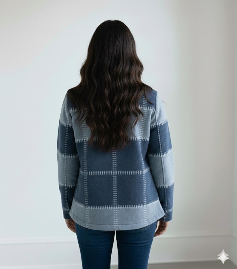 May include: A blue and grey plaid jacket with long sleeves. The jacket is worn by a person with long, dark hair. The jacket has a square pattern design and is made of a soft material. The person is wearing blue jeans.