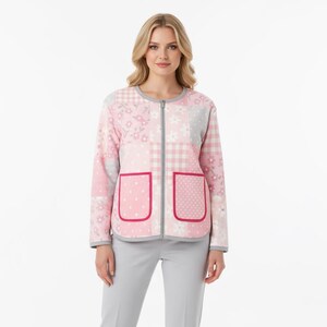 Pu&ograve; includere: Giacca rosa patchwork con finiture grigie e cerniera a tutta lunghezza. La giacca presenta due tasche frontali con finiture rosse. Il design patchwork include motivi floreali, a pois e a quadri. La modella indossa pantaloni grigi.