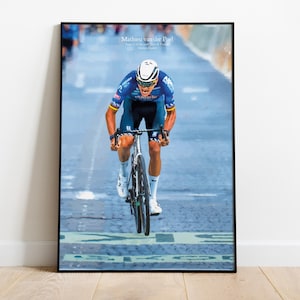 Könnte beinhalten: Ein gerahmtes Poster mit einem Radrennfahrer in einem blau-schwarzen Trikot auf einem Rennrad. Der Text "Mathieu van der Poel" steht oben. Der Radfahrer trägt einen weißen Helm und weiße Schuhe und hält den Lenker fest.