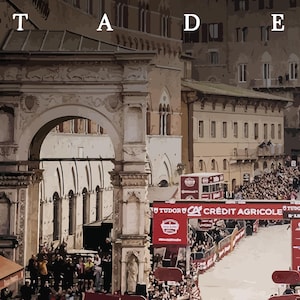 May include: A crowd of people gathered in a city square, with a large archway in the background. The archway is decorated with intricate carvings and has a sign that reads "Cr&eacute;dit Agricole".
