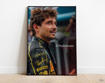 May include: A framed portrait featuring a man in a black and yellow racing suit. The image includes the text "Il Predestinato" and "The Chosen One" in red. The portrait is displayed on a white wall above a wooden floor.