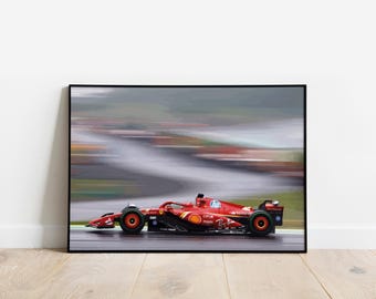 Könnte beinhalten: Ein roter Formel-1-Rennwagen rast über eine Rennstrecke, unscharf in Bewegung. Das Auto hat ein schwarz-weißes Sponsorenlogo an der Seite und der Fahrer trägt einen Helm.