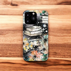 May include: A black phone case with a watercolor design of books, flowers, and stars. The case has a camera lens cutout and a black background.