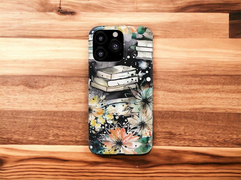 May include: A black phone case with a watercolor design of books, flowers, and stars. The case has a camera lens cutout and a black background.