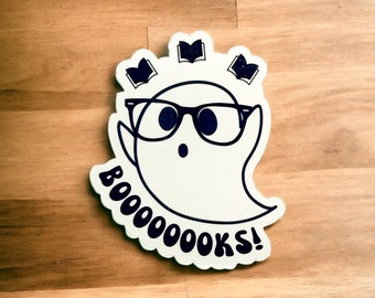 May include: A white ghost wearing black-rimmed glasses and a surprised expression. Three open books are floating above the ghost's head. The text "BOOOOOOOKS!" is written in a black, stylized font around the bottom of the ghost.