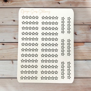 May include: A sheet of white sticker paper with black star stickers. The stickers are arranged in rows of five stars, with some rows having a single star at the end. The text "Ginger Snappy Stationery" is printed at the top of the sheet.