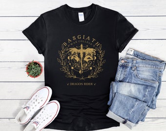 Peut inclure: T-shirt noir avec un motif doré d'un dragon avec le texte "Basgiath War College" et "Dragon Rider" sur fond blanc.