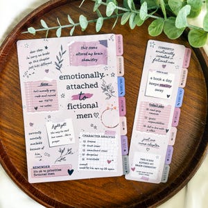 May include: A light purple reading journal and matching bookmark set featuring printed text and graphics. The journal includes sections for notes, character analysis, and reminders, with tabs labeled for favorite scenes and book boyfriend.