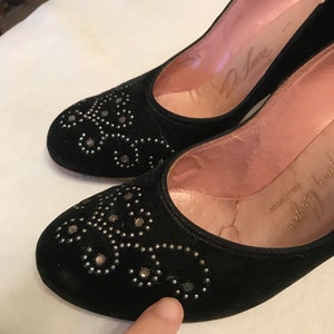 K&ouml;nnte beinhalten: Ein Paar schwarze Wildlederschuhe mit silbernen Nieten. Die Schuhe haben eine spitze Zehenpartie und einen niedrigen Absatz. Die Schuhe sind mit "De Luxe" gekennzeichnet und haben die Gr&ouml;&szlig;e "7 1/2 E 6 1/2" auf der Innenseite.