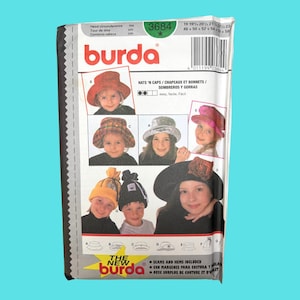 May include: A vintage Burda sewing pattern for hats and caps. The pattern features images of various hat styles, including a red cloche, a plaid hat, a silver hat, a pink hat, a yellow beanie, a black beanie, and a wide-brimmed hat. The pattern includes measurements in inches and centimeters.