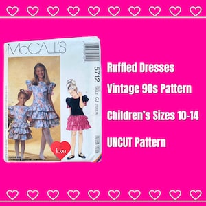 May include: Vintage 1990s McCall's sewing pattern for ruffled dresses in children's sizes 10-14. The pattern is uncut and includes instructions for making two different styles of dresses.