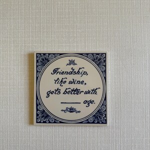 May include: Blue and white ceramic tile with a quote that reads "Friendship, like wine, gets better with age."