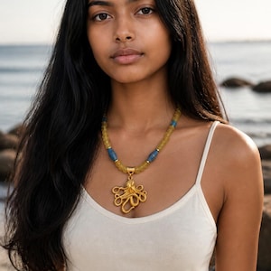 May include: A necklace featuring a gold-toned octopus pendant suspended from a strand of translucent yellow beads interspersed with cylindrical blue beads. The pendant displays a detailed, textured octopus design with curled tentacles.