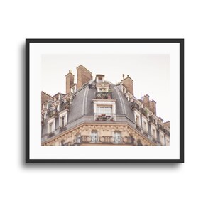 May include: A framed architectural print featuring the upper facade of a Parisian-style building with a curved slate roof, multiple chimneys, and wrought iron balconies. The structure displays light-colored stone walls and windows.