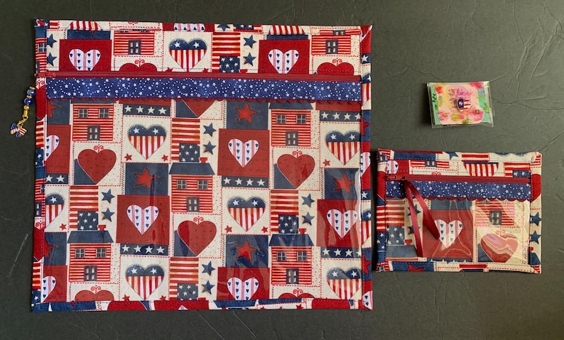 Pode incluir: Um conjunto de bolsas de tecido com tema patri&oacute;tico e um pequeno pacote. As bolsas apresentam um padr&atilde;o repetido de cora&ccedil;&otilde;es, casas e estrelas em vermelho, branco e azul. Uma bolsa tem um z&iacute;per e um berloque de contas.