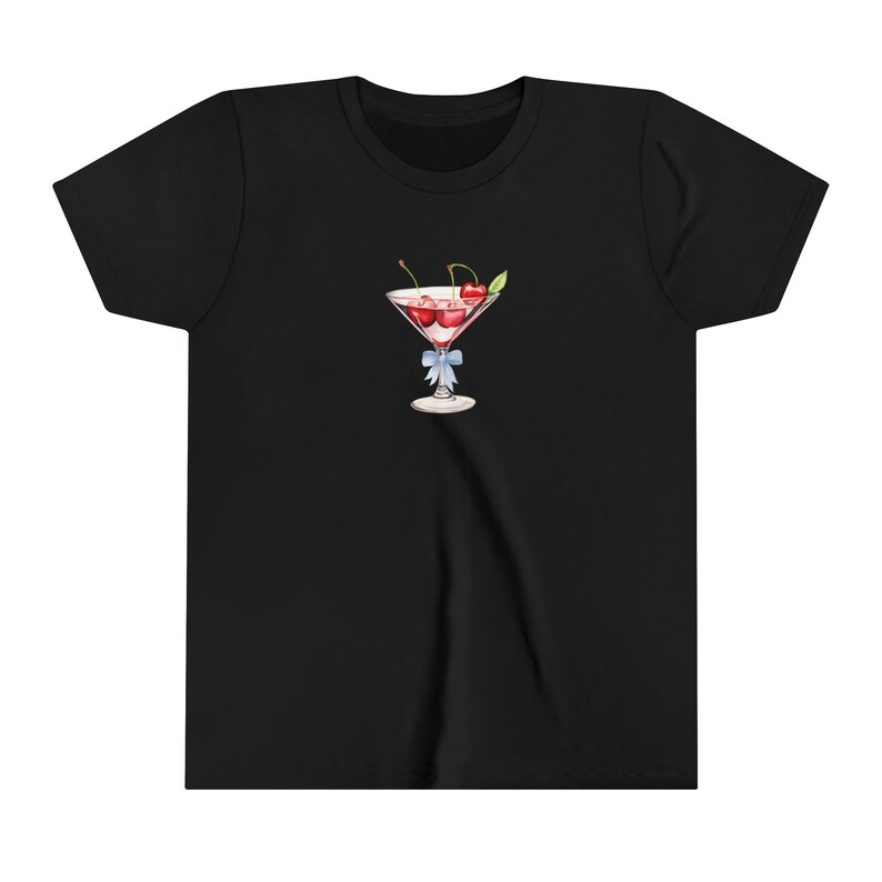 Peut inclure: T-shirt noir avec une illustration &agrave; l'aquarelle d'un verre &agrave; cocktail rempli de liquide rouge et de cerises. Un n&oelig;ud bleu clair est nou&eacute; autour de la tige. Le motif est centr&eacute; sur le devant du t-shirt.