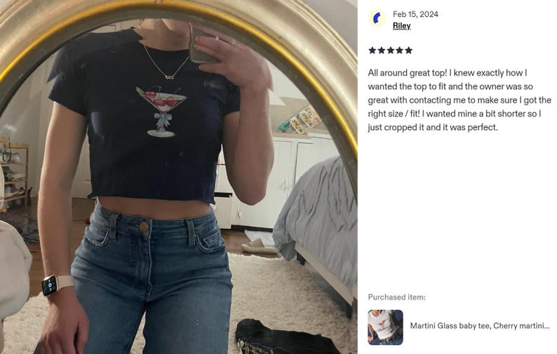 Peut inclure: Haut court bleu marine avec un motif de verre &agrave; martini et une cerise. Le haut est port&eacute; avec un jean bleu. L'image est refl&eacute;t&eacute;e dans un miroir.