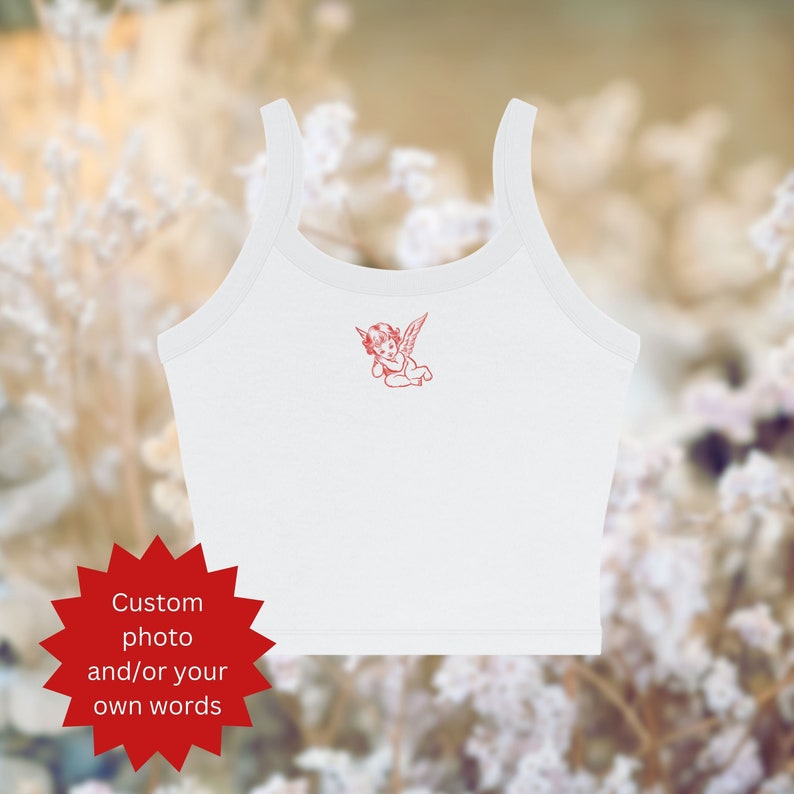 Puede incluir: Top blanco de tirantes con un gr&aacute;fico de &aacute;ngel rojo. El top es de estilo corto y tiene un escote redondo. El texto "Custom photo and/or your own words" est&aacute; en una estrella roja.