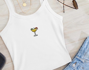 Puede incluir: Camiseta blanca de tirantes con una pequeña imagen bordada de una copa de margarita con una rodaja de lima y un chile.