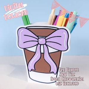 Puede incluir: Un portalápices con forma de taza de café, decorado con un lazo lila claro. La taza está llena de bolígrafos y lápices. El texto de la imagen dice "DESCARGA DIGITAL" y "PEN HOLDER 3MF FILE SMALL COMMERCIAL USE INCLUDED".