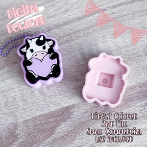 Puede incluir: Un fidget clicker en forma de vaca de color púrpura claro que sostiene un corazón, con un molde rosa a juego en forma de vaca. La vaca tiene marcas en blanco y negro. El texto de la imagen dice "DESCARGA DIGITAL" y "FIDGET CLICKER 3MF FILE SMALL COMMERCIAL USE INCLUDED."