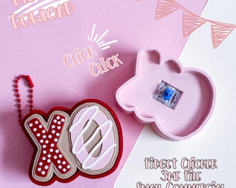 May include: A pink fidget clicker with a blue switch and a red XO keychain. The XO keychain is red with white polka dots and a donut-shaped O with pink icing. Text includes "Digital Download" and "Click Click".