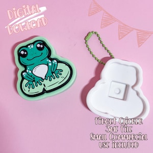 Può includere: Un fidget clicker a forma di rana verde e un fidget clicker bianco con una catena verde su sfondo rosa. La rana ha la pancia bianca ed è seduta su una foglia di ninfea. Il testo include "Download digitale" e "Fidget Clicker 3MF File Small Commercial Use Included".