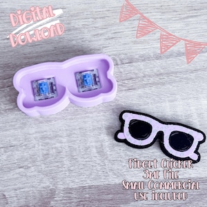 Puede incluir: Un juguete fidget de color lila claro con forma de gafas con dos interruptores de teclado mecánico azules. También hay un juguete fidget con forma de gafas en blanco y negro. La imagen incluye el texto "Digital Download" y "Fidget Clicker 3MF File Small Commercial Use Included."