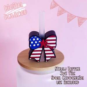 May include: A straw topper with a patriotic bow design featuring the American flag. The bow is red, white, and blue, with a star-studded blue section and red and white stripes. The topper sits on a wooden lid.