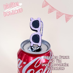 Puede incluir: Una lata de refresco roja con tapa plateada, con un abridor de latas en forma de gafas de sol moradas. Las gafas de sol tienen lentes negras y lunares blancos. El texto en la lata dice "Soda Can Opener 3MF File Small Commercial Use Included".
