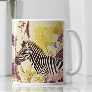 May include: White ceramic mug with a zebra design. The zebra has black and white stripes, set against a backdrop of yellow and purple floral elements. The mug has a white handle and a glossy finish.