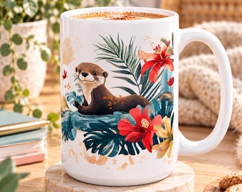 Può includere: Una tazza in ceramica bianca con una colorata illustrazione di una lontra marrone circondata da vivaci fiori di ibisco rossi e un rigoglioso fogliame tropicale verde. La tazza è dotata di un ampio manico.