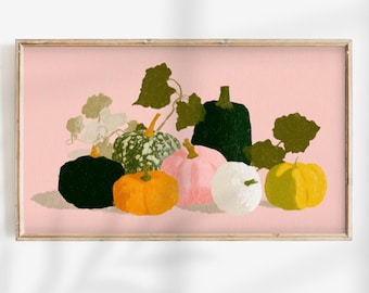 May include: A framed print featuring a still life of colorful pumpkins and gourds. The pumpkins are in shades of black, orange, pink, white, green, and yellow, with green leaves and vines against a soft pink background. The artwork is in a rectangular wooden frame.