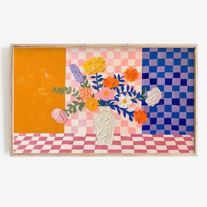 以下が含まれることがあります： 色とりどりの花が活けられた白い花瓶が描かれた額入りの絵画。背景は、オレンジ色、ピンクと白のチェック柄、青と紫のチェック柄に分かれています。花には、黄色、オレンジ色、ピンク色、白色の花が含まれています。