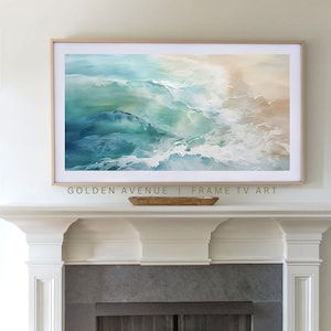 May include: Abstract painting of ocean waves in shades of blue, green, and white, framed in a light wood frame, hanging above a white fireplace mantel. The text "GOLDEN AVENUE | FRAME TV ART" is below the painting.