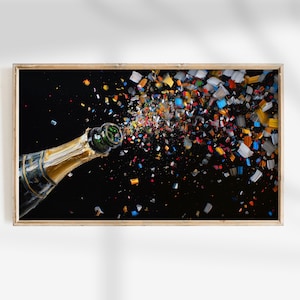 Könnte beinhalten: Gerahmter Kunstdruck einer Champagnerflasche, die geöffnet wird, mit bunten Konfetti, die herausspritzen. Die Flasche hat einen goldenen Hals und einen grünen Verschluss. Der Hintergrund ist schwarz, und der Rahmen ist helles Holz.