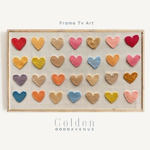 May include: A framed wall art piece featuring a collection of 25 colourful woven hearts in a variety of shades, including red, orange, yellow, green, blue, purple, and pink. The hearts are arranged in a grid pattern on a beige background. The frame is made of natural wood and has a simple design. The text "Frame Tv Art" is printed above the hearts, and the text "Golden OOOOAVENUE" is printed below the hearts.