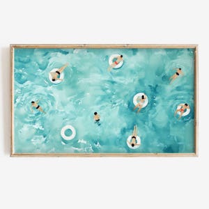 May include: An aerial view of a turquoise blue pool with people floating on white inflatable rings. The people are wearing swimsuits and are enjoying the water.