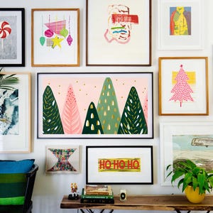 Puede incluir: Una pared de galer&iacute;a con una variedad de obras de arte enmarcadas, que incluyen pinturas abstractas, ilustraciones y una impresi&oacute;n de un bast&oacute;n de caramelo. La pared est&aacute; pintada de blanco y presenta una silla negra con un coj&iacute;n a rayas azul y verde. Las obras de art incluyen una impresi&oacute;n de un &aacute;rbol de Navidad, una impresi&oacute;n de un bosque y una impresi&oacute;n con el texto "Ho Ho Ho".