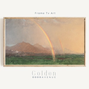 May include: A framed painting of a landscape with two rainbows in the sky. The landscape features a field of green grass, a mountain range in the distance, and a cloudy sky. The painting is in a gold frame.