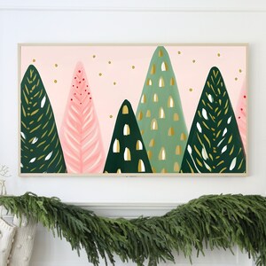 Puede incluir: Una impresi&oacute;n enmarcada de una escena de bosque abstracto en tonos rosa y verde con detalles dorados. La impresi&oacute;n est&aacute; colgada sobre una repisa de chimenea decorada con una guirnalda de ramas de con&iacute;feras.