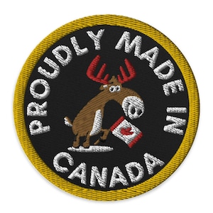 May include: A round, yellow-bordered patch with a black background. The text "Proudly Made in Canada" is written in white around the edge of the patch. A cartoon moose with red antlers is holding a red and white Canadian flag in its front hooves.