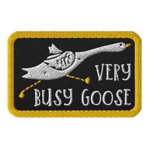 May include: A black and yellow embroidered patch featuring a white goose in flight with the text "Very Busy Goose".