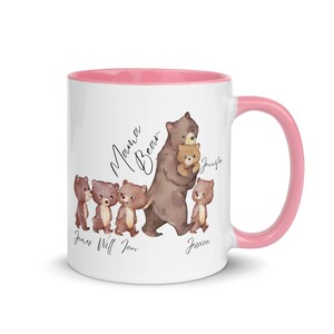 May include: White ceramic mug with a pink rim and handle. The mug features a watercolor illustration of a mama bear and four cubs. The text "Mama Bear" is written above the bears. The cubs are labeled with the names "James", "Will", "Ian", and "Jessica".
